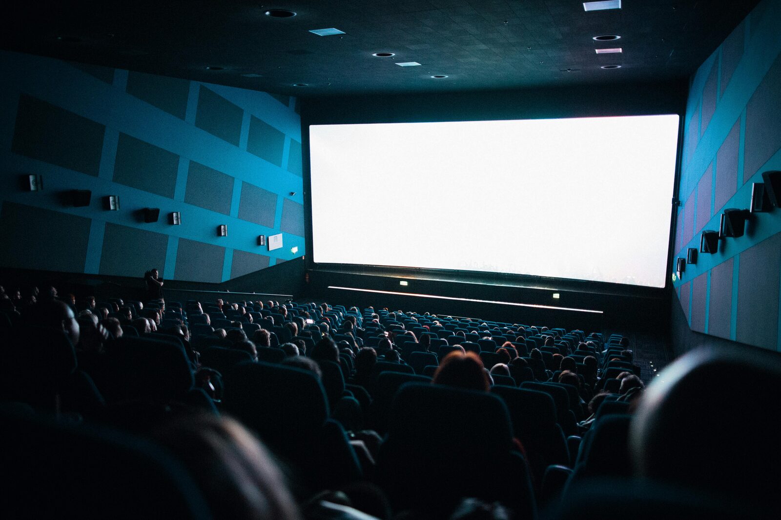 Cinema audience seated in a dark theater watching a film on a large screen