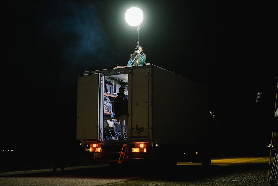 Film electricians operating a lighting truck at night on a movie production, balloon light rigged above the vehicle