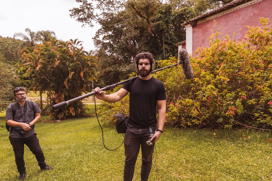 Film crew director and boom operator working on location with boom pole extended