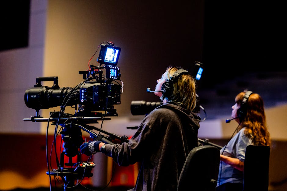 Camera operator and crew member operating a professional cinema camera rig on a dark production set