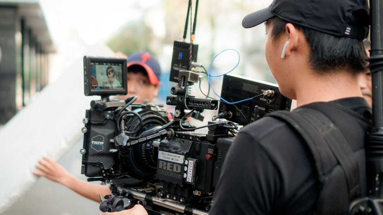 Camera crew operating a RED cinema camera with on-board monitor during an outdoor shoot