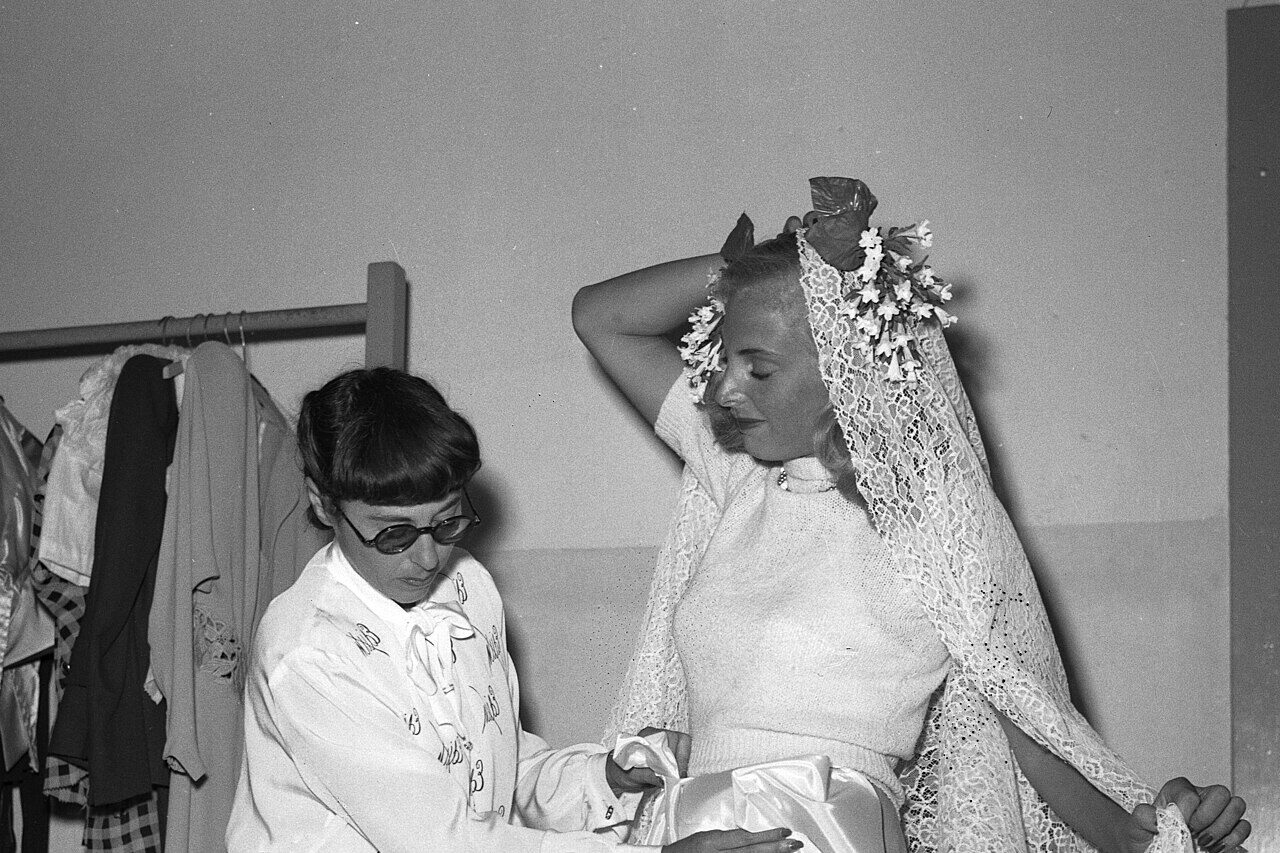Edith Head fitting a wedding gown on a model in a Hollywood studio wardrobe room, circa 1940s