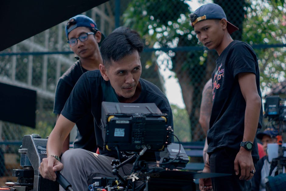 Film director reviewing footage on a professional camera monitor with crew members on set outdoors