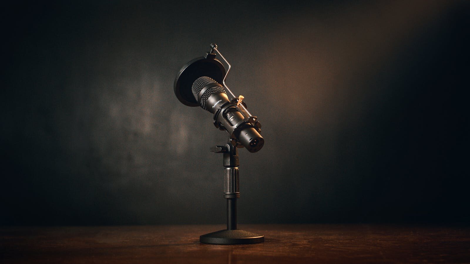 Professional condenser microphone with pop filter on a stand, dramatically lit with warm golden tones against a dark background