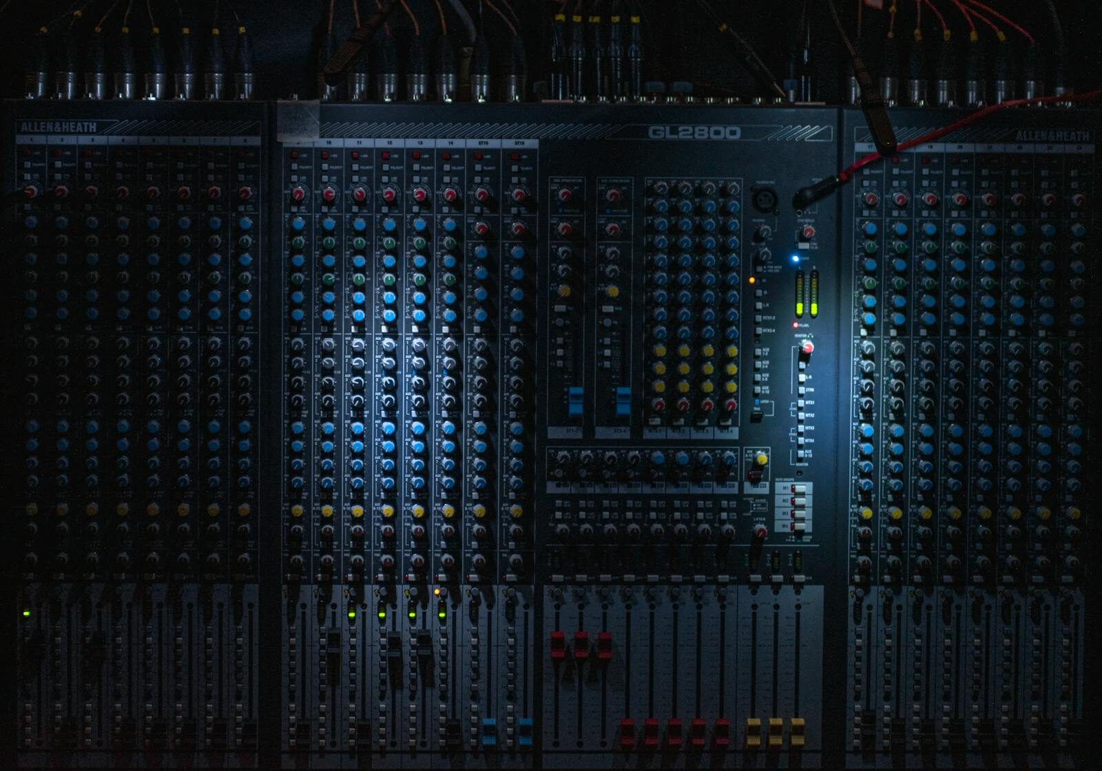 Close-up of a professional sound mixing console in a dark studio with blue LED indicator lights