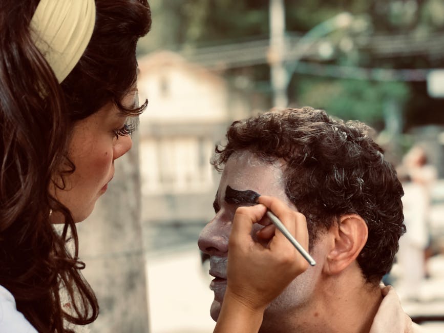 Makeup artist applying precise stage makeup with a fine brush to a performer in close-up during a production