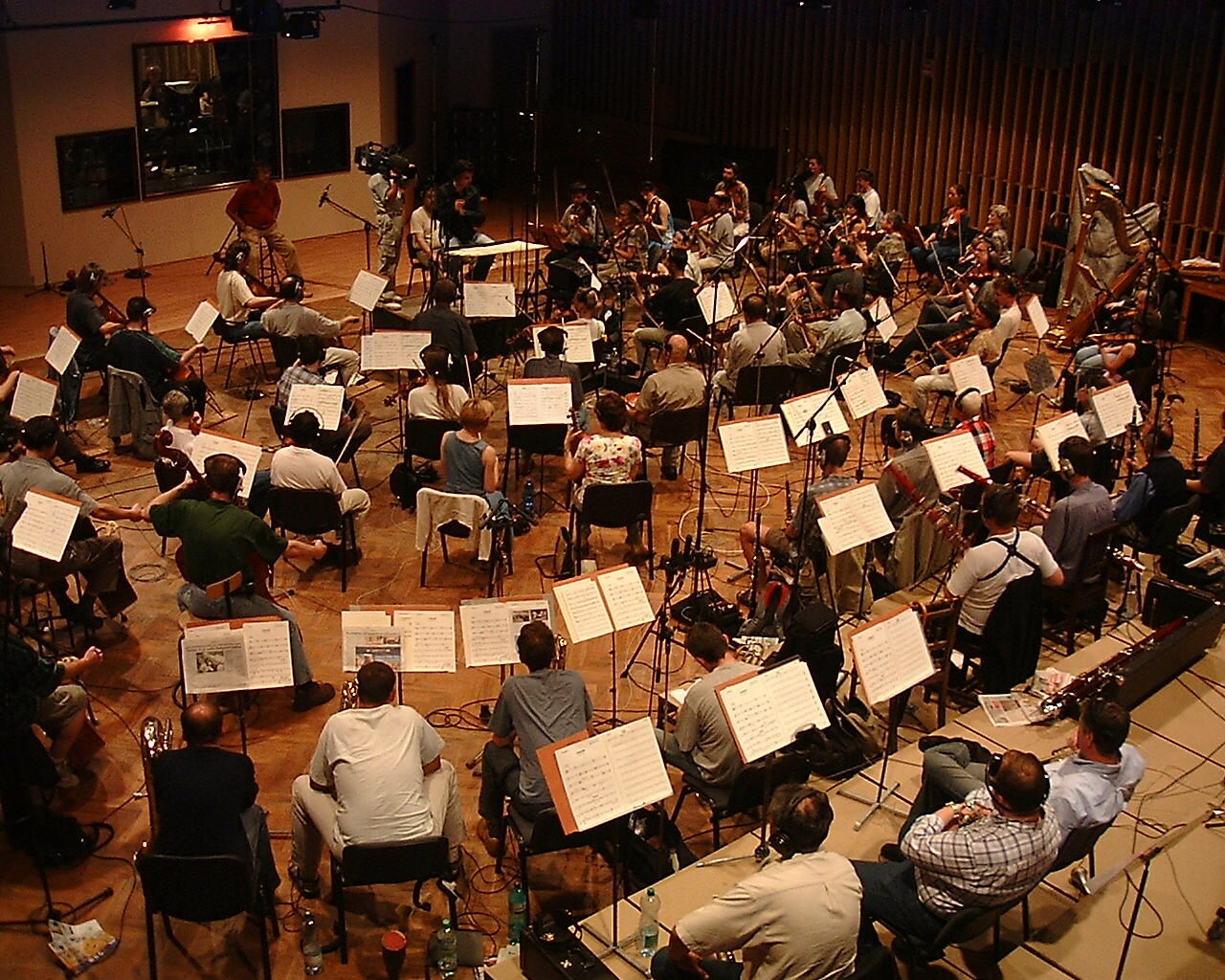 Orchestra performing in a professional recording studio during a film scoring session, musicians with sheet music under studio lighting