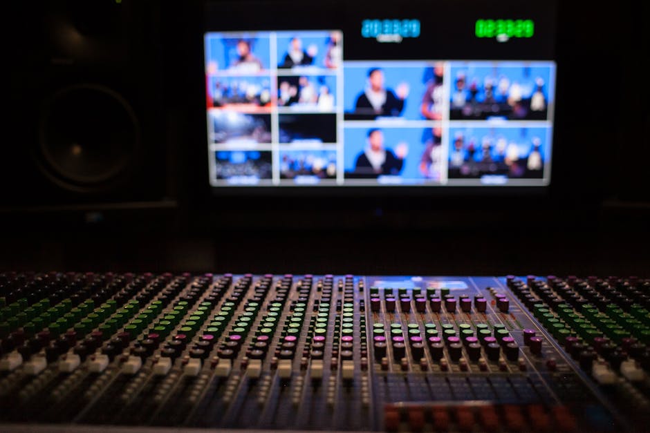 Sound mixing console with film footage visible on screens in a dark post-production studio