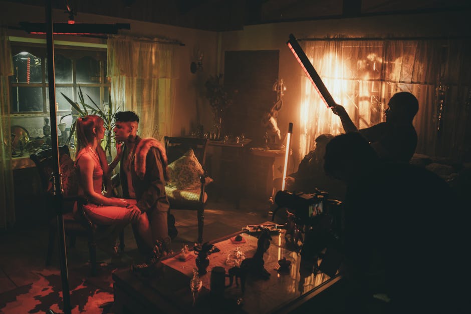 Film crew adjusting LED tube lighting on a fully dressed interior set with period furniture and props