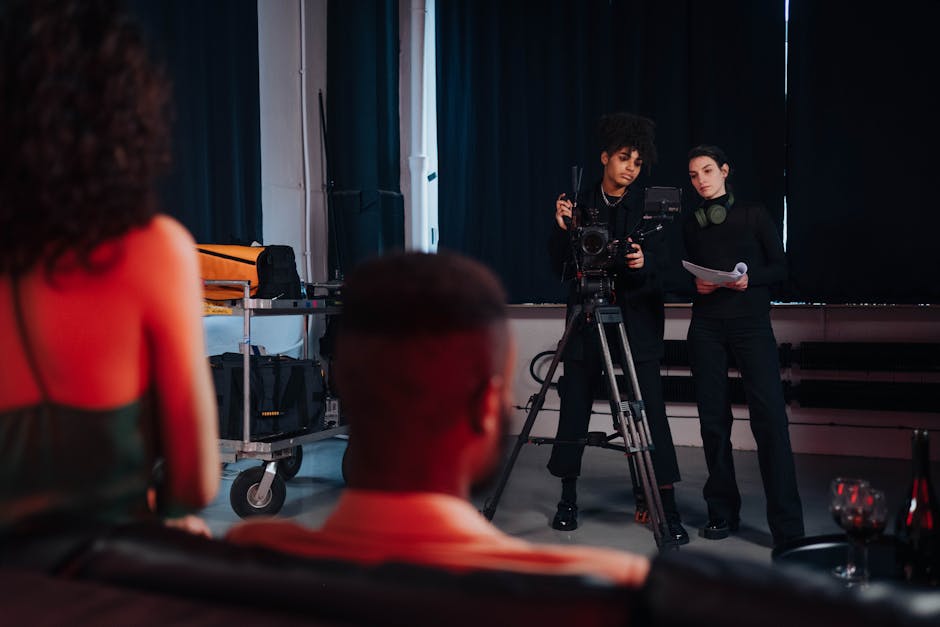 Film crew members on set — camera operator and production coordinator reviewing documents beside camera on tripod