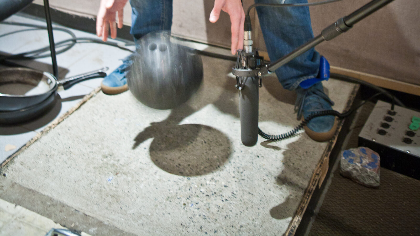 Foley recording session showing a microphone capturing footstep sounds on a concrete surface in a sound design studio