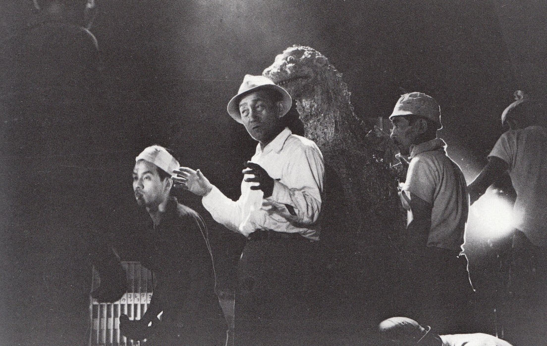 Eiji Tsuburaya directing his special effects crew on the set of Godzilla 1954, with the Godzilla suit visible behind him