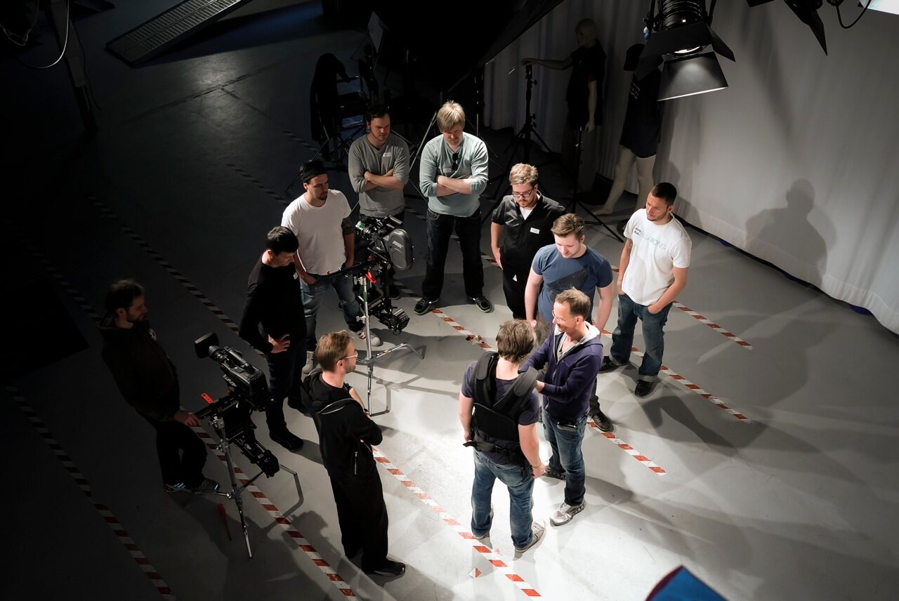 Steadicam operator workshop session with multiple crew members gathered around an operator demonstrating the rig in a studio