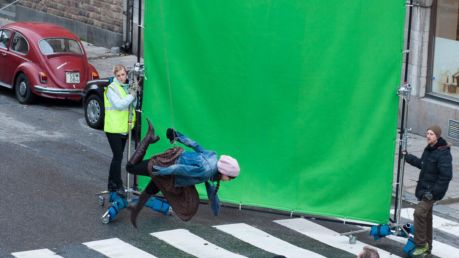 Stunt performer Madeleine Trollvik rigged on a wire against a green screen on a film set street location